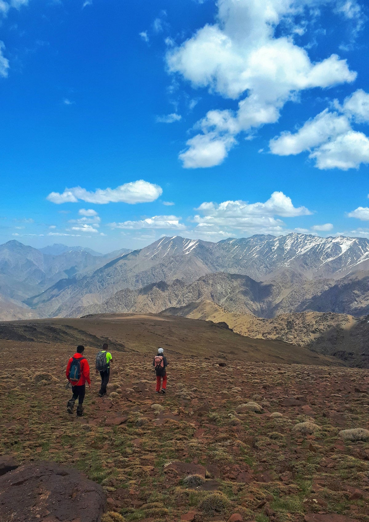 Walkers on a dirt path in front of the Atlas mountain range